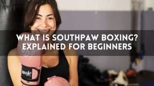 Smiling woman wearing pink boxing gloves with text overlay that reads “What Is Southpaw Boxing? Explained for Beginners.”