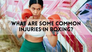 Female boxer in a defensive stance wearing red gloves in front of a graffiti wall, with the text "What Are Some Common Injuries in Boxing?" displayed across the image.